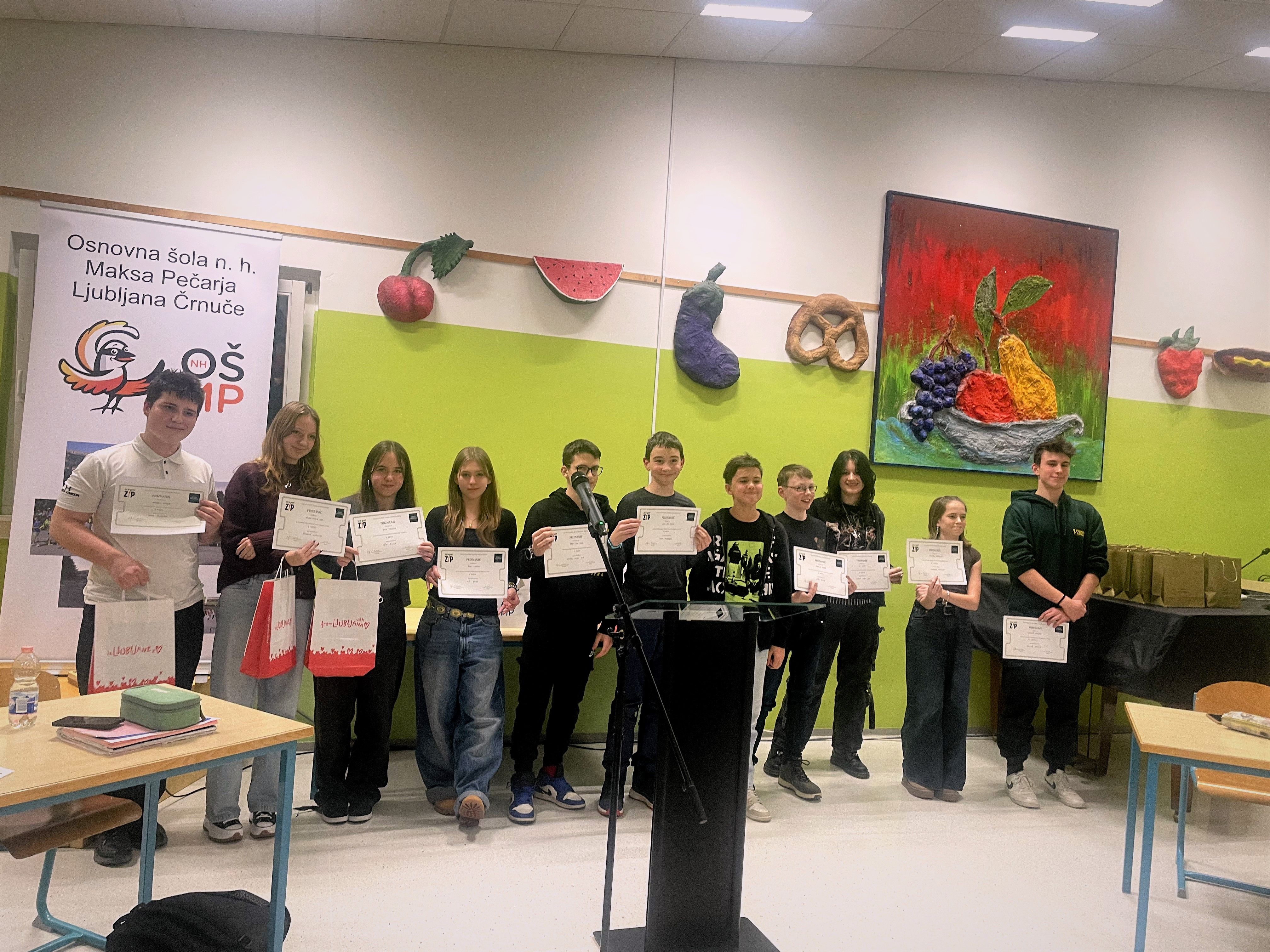 SKupinska fotografija vseh finalistov izbornega turnirja osnovnih šol v rjketu Mojstri digitalne prihodnosti, na sliki je 11 osnovnošolcev, ki držijo v rokah priznanja.