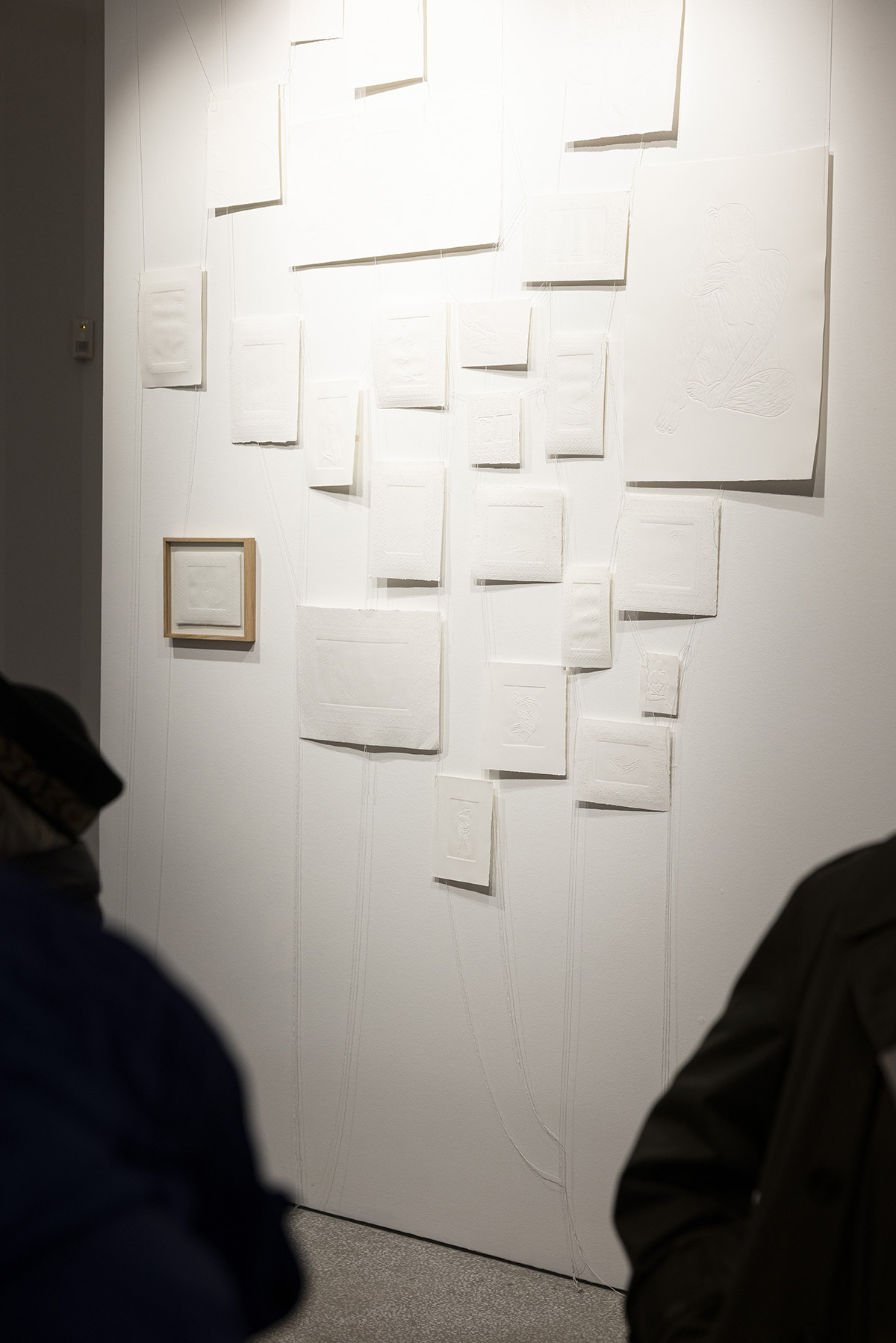 Obiskovalci si ogledujejo razstavljene grafike