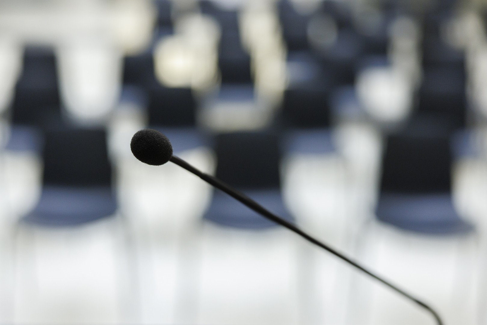 Namizni mikrofon, za njim v zamegljenem ozadju prazni stoli