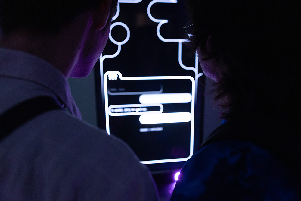 A man is looking at illuminated panels displayed in a gallery.