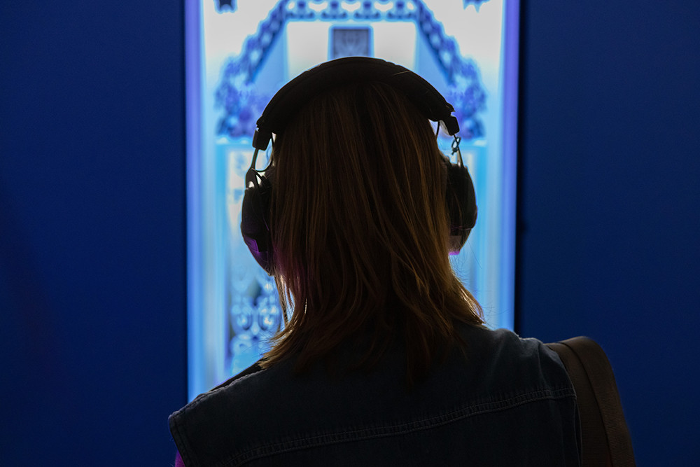 A man is looking at illuminated panels displayed in a gallery.