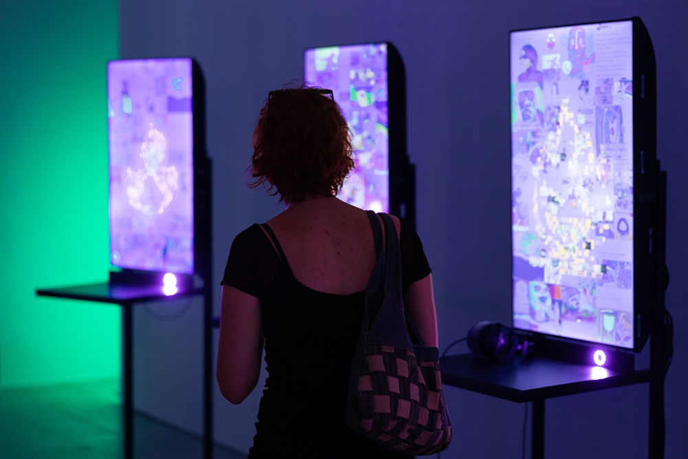 A man is looking at illuminated panels displayed in a gallery.