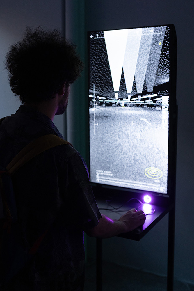 A man is looking at illuminated panels displayed in a gallery.