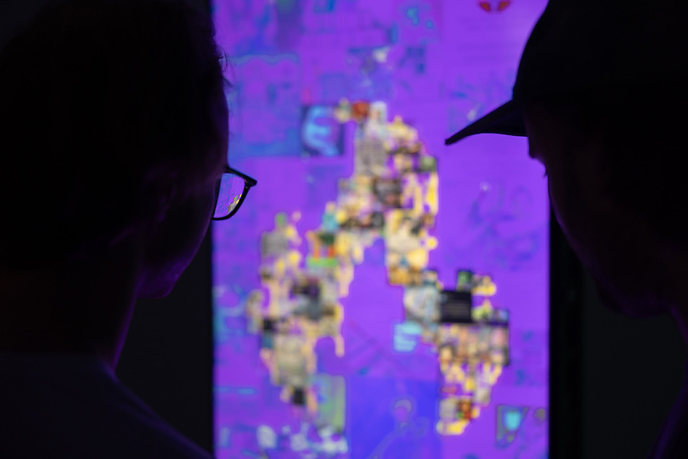 A man is looking at illuminated panels displayed in a gallery.