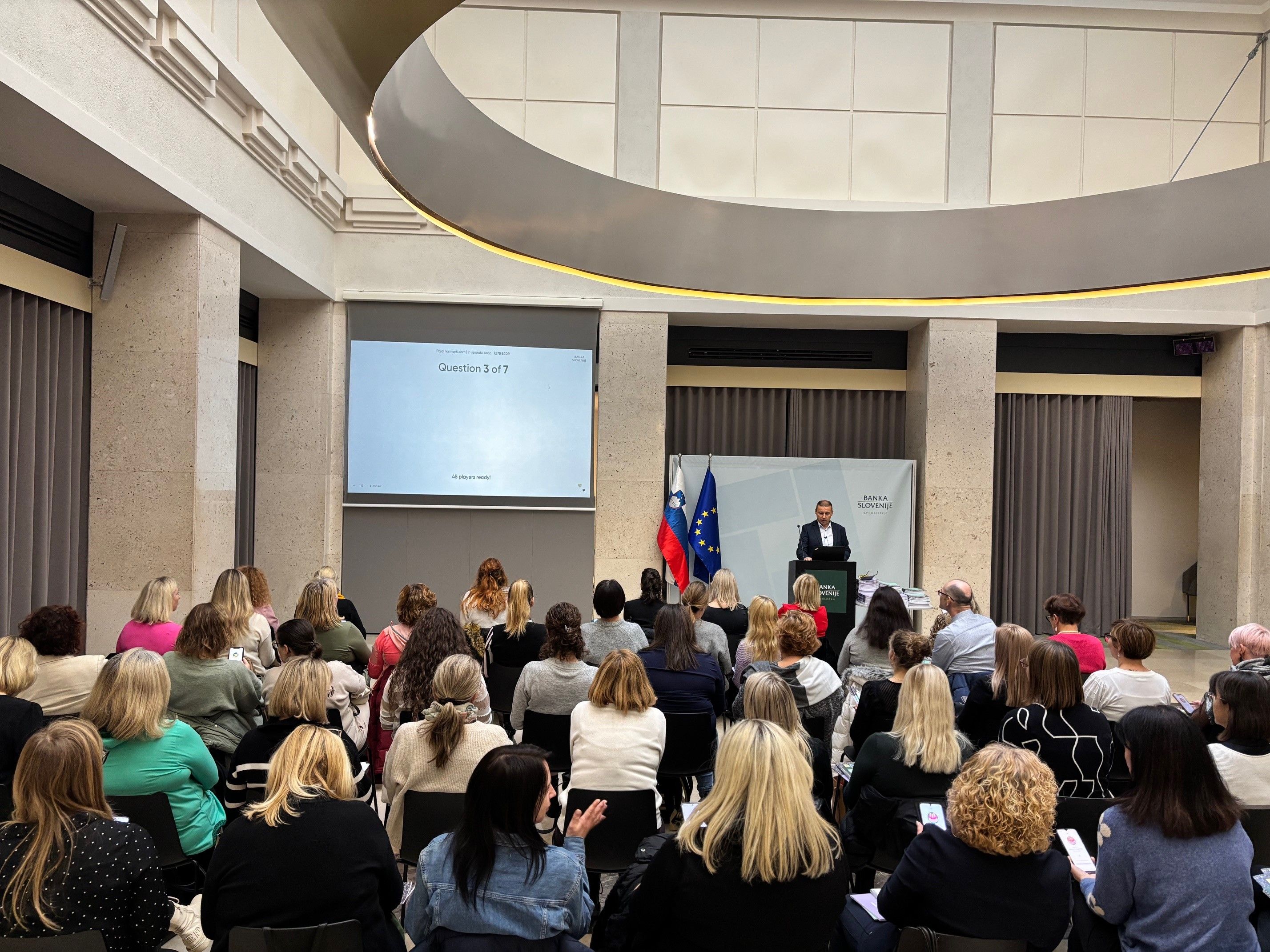 PRedavalnica polna učiteljev, kjer predavatelj pojasnjuje ob prezentaciji